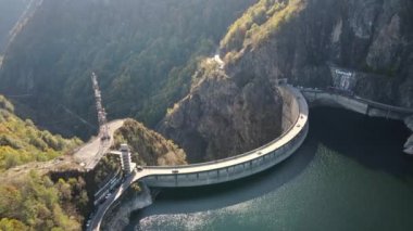 Romanya 'da doğanın insansız hava aracı görüntüsü. Vidraru barajı ve gölü olan Karpat dağlarındaki vadi, yemyeşil ormanlı yamaçlar.
