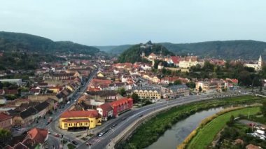 Romanya 'nın Sighisoara Tarih Merkezi' nin insansız hava aracı görüntüsü. Eski binalar, yemyeşil sokaklar, arabalar, nehir