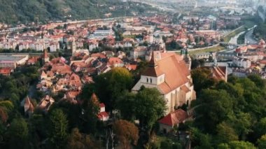 Romanya 'nın Sighisoara Tarih Merkezi' nin insansız hava aracı görüntüsü. Eski binalar, tepedeki kilise, yeşilliklerle çevrili.