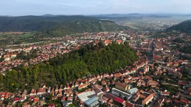 Aerial drone view of Sighisoara, Romania. Old buildings, greenery, roads with cars, hills