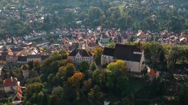 Romanya 'nın Sighisoara Tarih Merkezi' nin insansız hava aracı görüntüsü. Eski binalar, tepedeki kilise, yeşilliklerle çevrili.