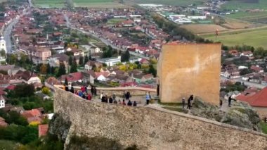 Romanya 'daki Rupea Kalesi' nin insansız hava aracı görüntüsü. Kale bir uçurumun kenarında, turistler, kasaba