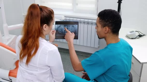 白人女牙医向学生解释X光片 背景的内阁装备 — 图库视频影像