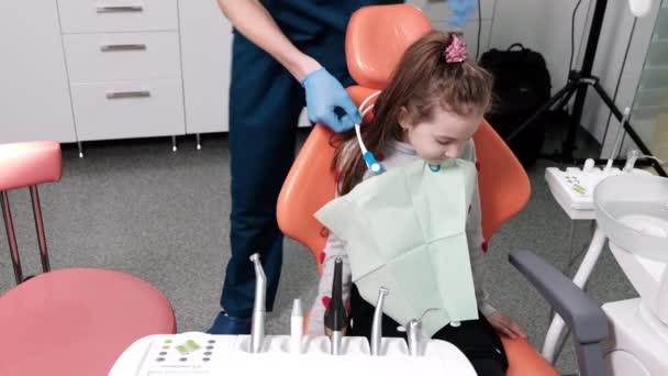 Kinderpatient Wartet Behandlungsstuhl Während Der Arzt Der Zahnarztpraxis Schutzmaterialien Anlegt — Stockvideo