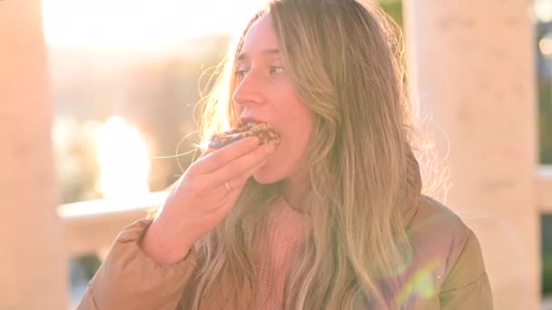 日没時に公園でチョコレートドーナツを食べる女性 — ストック動画
