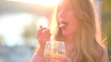 Gün batımında parkta meyve salatası yiyen bir kadın.