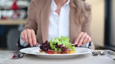 Restoranda sebzeli biftek salatası yiyen bir kadın.