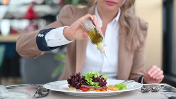 Frau Isst Rindfleischsalat Mit Gemüse Einem Restaurant Und Toppt Olivenöl — Stockvideo
