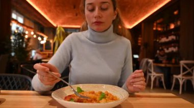 Restoranda domatesli İtalyan gnocchi yiyen bir kadın.