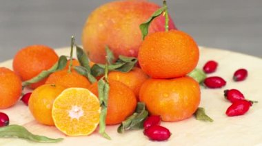 Dilimlenmiş portakal, mango, gül kalemi ve yeşil yapraklı bileşim, su damlacıklarıyla kapat