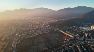 Romanya 'nın güneş doğarken Brasov' un insansız hava aracı görüntüsü. Yollar, konut binaları, sarı ağaçlar, Karpatlar