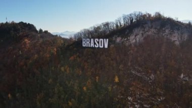 Kentin yakınındaki tepenin tepesinde Brasov tabelası, Romanya 'nın sararmış ağaçları