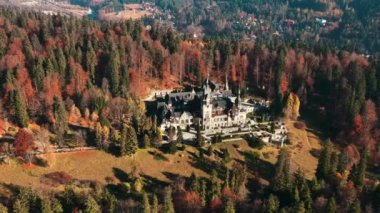 Romanya 'daki Peles Kalesi' nin insansız hava aracı görüntüsü. Karpatlar 'da bahçeli bir kale, etrafında orman, turistler.