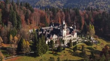 Romanya 'daki Peles Kalesi' nin insansız hava aracı görüntüsü. Karpatlar 'da bahçeli bir kale, etrafında orman, turistler.