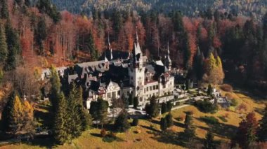 Romanya 'daki Peles Kalesi' nin insansız hava aracı görüntüsü. Karpatlar 'da bahçeli bir kale, etrafında orman, turistler.