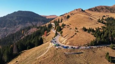 Romanya 'nın Bucegi Dağları' ndaki bir yolun insansız hava aracı görüntüsü. Park etmiş ve hareket eden arabalar, yeşil köknarlar.