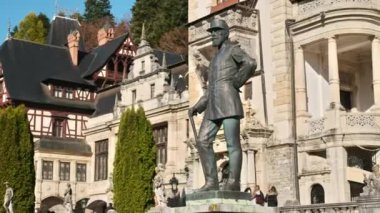 Romanya 'daki Peles Kalesi' nde Kral Carol heykeli. Kale arka planda, turistler