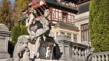 Romanya 'daki The Peles Castle' daki heykelin dikey görüntüsü. Kale arka planda, turistler