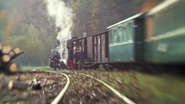 VISEU DE SUS, ROMANIA - OCTOBER 29, 2021: View of the steam train Mocanita in a valley on a railway station, workers. Lensbaby effect