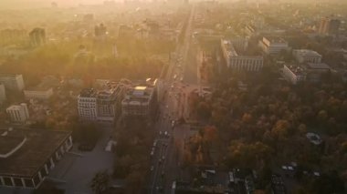 Chisinau 'nun sonbaharda gün batımında Moldova' da hava aracı görüntüsü. Sarı bitki örtüsü, birden fazla bina, arabalı yollar, yavaş çekim