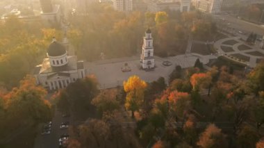 Chisinau 'nun sonbaharda gün batımında Moldova' da hava aracı görüntüsü. Sarı ağaçlar ve insanlar ile Central Park, Katedral, yavaş çekim