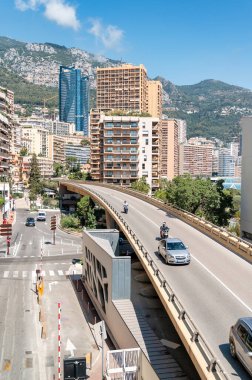 MONACO - 21 AĞUSTOS 2021: Yol, köprü hareket eden arabalar, binalar, yeşillik, arka planda tepeler
