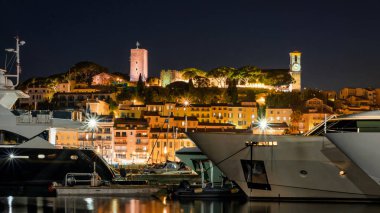 Fransa 'da gece Cannes manzarası. Limanda demirli yatlar, arka planda şehir manzarası, gece lambaları.