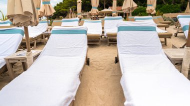 Fransa 'nın Sainte-Marguerite adasında güneşli yataklı ve şemsiyeli Akdeniz sahili manzarası