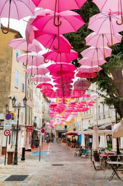 GRASSE, FRANCE - 3 Eylül 2021: şehrin sokak manzarası. Pembe şemsiyeli dar sokaklar