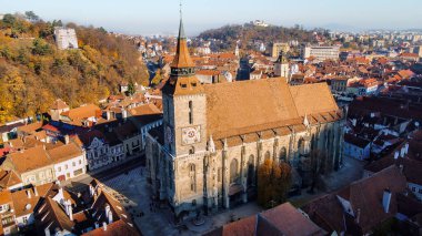 Romanya 'nın Brasov kentindeki Kara Kilise' nin insansız hava aracı görüntüsü. Binaları ve sarı ağaçları olan eski şehir merkezi.