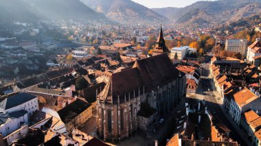 Romanya 'nın Brasov kentindeki Kara Kilise' nin insansız hava aracı görüntüsü. Binaları ve sarı ağaçları olan eski şehir merkezi.