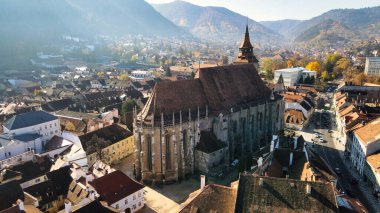 Romanya 'nın Brasov kentindeki Kara Kilise' nin insansız hava aracı görüntüsü. Binaları ve sarı ağaçları olan eski şehir merkezi.