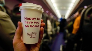 IASI, ROMANIA - Kasım 2021: Wizzair logosu ve uçakta mesaj taşıyan bir erkek el