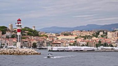 Fransa 'da yüzen bir tekneden Cannes manzarası. Geleneksel tarzda yapılmış çok sayıda bina, deniz fenerli liman.