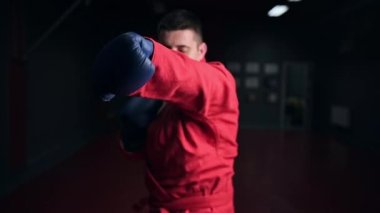 Kırmızı kimonolu ve eldivenli tekvando antrenörü önünde spor salonunda boks yapıyor. Yavaş çekim