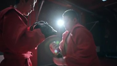 Kırmızı kimonolu tekvando antrenörü spor salonunda antrenman yapıyor. Yavaş çekim