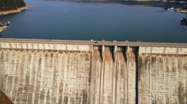 Romanya 'daki arabalarla Bicaz gölü ve barajının insansız hava aracı görüntüsü. Tepeler yemyeşil ormanlarla kaplı.