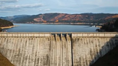 Romanya 'daki arabalarla Bicaz gölü ve barajının insansız hava aracı görüntüsü. Tepeler yemyeşil ormanlarla kaplı.