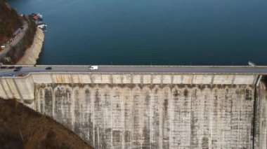 Romanya 'daki arabalarla Bicaz gölü ve barajının insansız hava aracı görüntüsü. Tepeler yemyeşil ormanlarla kaplı.