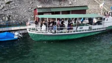 BICAZ, ROMANIA - NOVEMBER, 2021: Bicaz Gölü 'ndeki insanlı bir teknenin insansız hava aracı görüntüsü