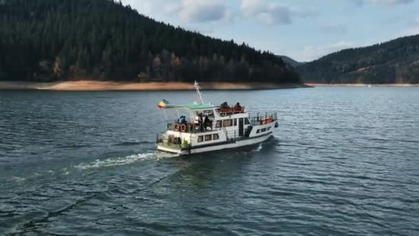 在罗马尼亚的Bicaz湖上 一架载有乘客的船被无人驾驶飞机拍到 覆盖着茂密森林的小山 — 图库视频影像