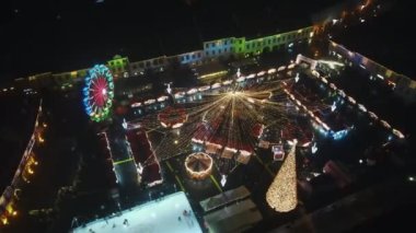 Romanya 'nın Sibiu kentindeki Büyük Meydan' ın insansız hava aracı görüntüsü. Noel için dekore edilmiş eski şehir merkezi. Dönme dolap, buz pateni pisti, eski geleneksel binalar, insanlar