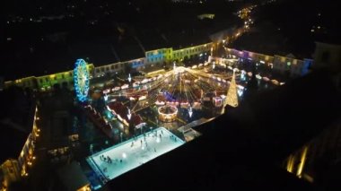Romanya 'nın Sibiu kentindeki Büyük Meydan' ın insansız hava aracı görüntüsü. Noel için dekore edilmiş eski şehir merkezi. Dönme dolap, buz pateni pisti, eski geleneksel binalar, insanlar