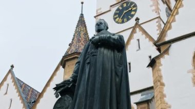Romanya 'nın Sibiu kentindeki Piskopos Georg Daniel Teutsch' un heykeli. Arka planda Sibiu Lutheran Katedrali