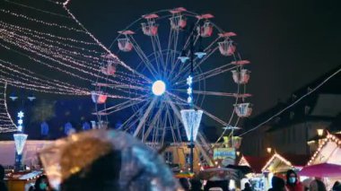 SIBIU, ROMANIA - 2021 ARALIK: gece şehir merkezindeki Büyük Meydan manzarası. Noel için dekore edilmiş eski şehir merkezi, eski geleneksel binalar, birden fazla insan, dönme dolap.