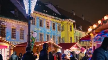 SIBIU, ROMANIA - 2021 ARALIK: gece şehir merkezindeki Büyük Meydan manzarası. Noel için dekore edilmiş eski şehir merkezi, eski geleneksel binalar, birden fazla insan