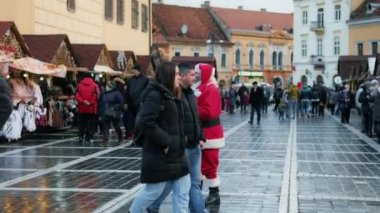 BRASOV, ROMANIA - 2021 ARALIK: Konsey Meydanı. Noel için dekore edilmiş eski şehir merkezi, Noel Baba, birden fazla insan