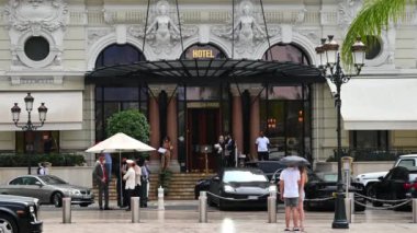 MONACO - EPTEMBER, 2021: Hotel de Paris girişi, güvenlik, önündeki insanlar ve arabalar, yağmur