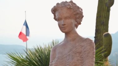 Fransa, Menton 'da tropikal bitkilerle dolu bir parkta heykel. Arka planda deniz