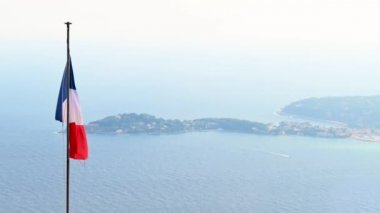 Ulusal bayrağı olan bir çatı, arka planda Menton, Fransa 'da deniz kıyısı. Yavaş çekim
